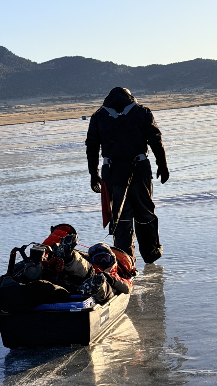 Hauling my son across the ice on a sled at Eleven Mile Reservoir — ice fishing together in the dead of winter