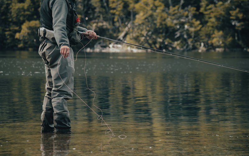 Angler feeding line for a controlled drift on flat water (photo: Unsplash)