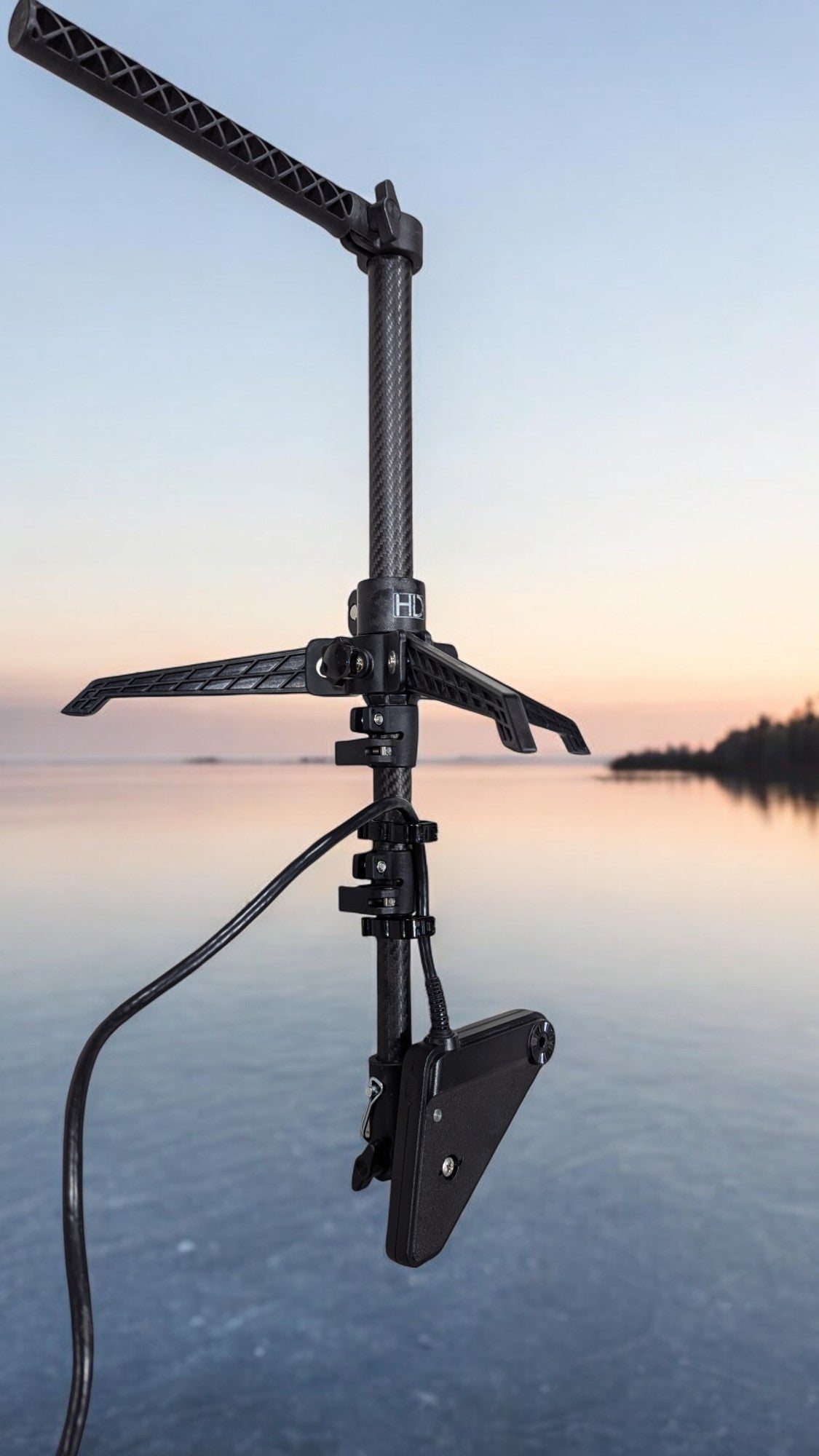 An HD Innovations X-Over carbon pole and tripod on the ice at dusk, forward-facing-sonar transducer mounted and ready